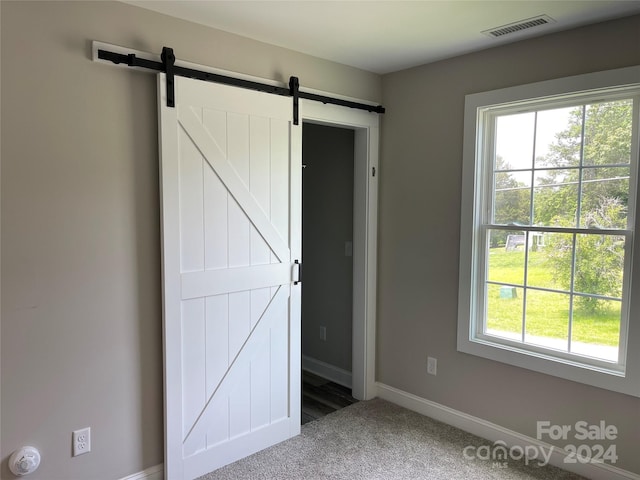 unfurnished bedroom featuring a barn door and carpet flooring