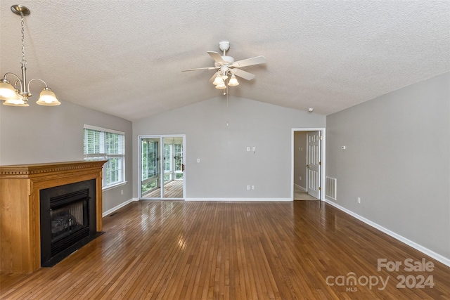 unfurnished living room with a textured ceiling, ceiling fan with notable chandelier, vaulted ceiling, and dark wood-type flooring