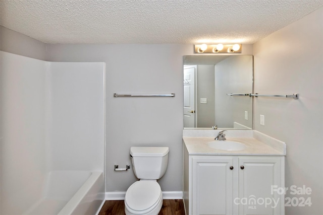 full bathroom featuring washtub / shower combination, hardwood / wood-style floors, a textured ceiling, toilet, and vanity