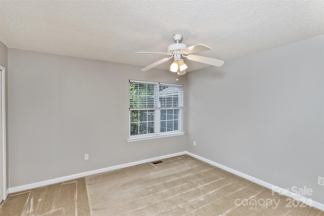 empty room with ceiling fan, carpet floors, and a textured ceiling