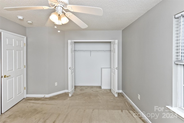 unfurnished bedroom with ceiling fan, light colored carpet, a textured ceiling, and a closet