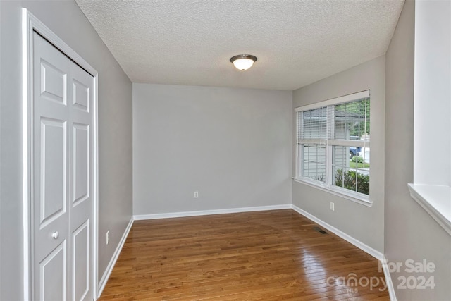 empty room with wood-type flooring and a textured ceiling