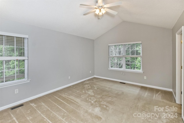 carpeted empty room featuring ceiling fan, a healthy amount of sunlight, and vaulted ceiling