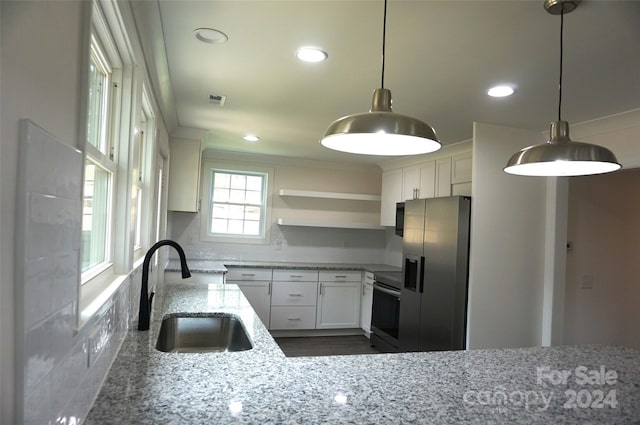 kitchen with sink, white cabinetry, hanging light fixtures, light stone countertops, and appliances with stainless steel finishes