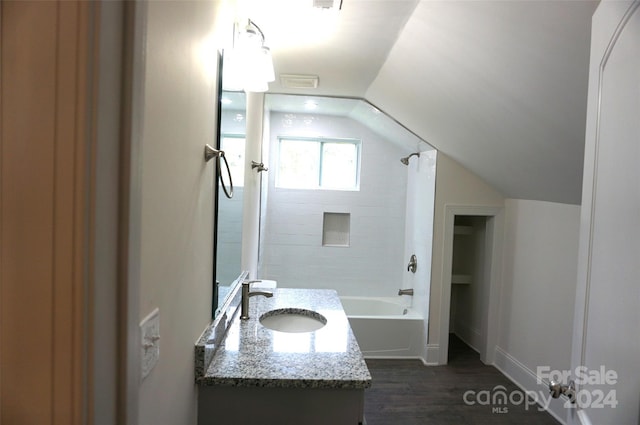 bathroom featuring hardwood / wood-style flooring, tiled shower / bath combo, vanity, and lofted ceiling