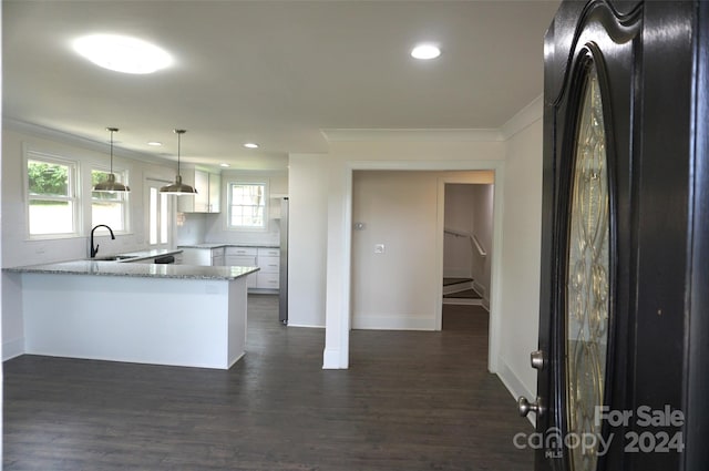 kitchen with light stone countertops, white cabinets, decorative light fixtures, kitchen peninsula, and crown molding