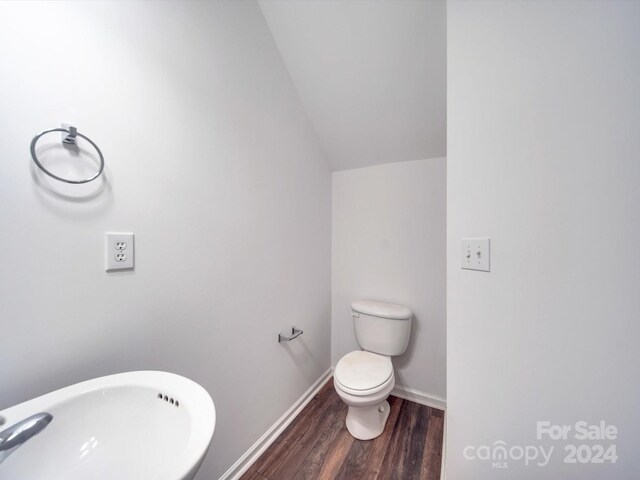 bathroom with toilet, sink, vaulted ceiling, and hardwood / wood-style flooring