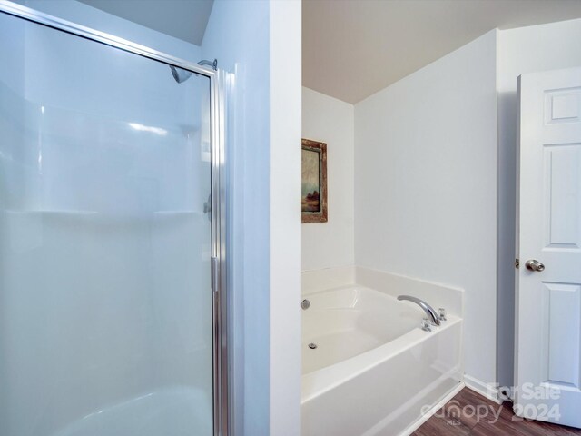 bathroom with hardwood / wood-style floors and shower with separate bathtub