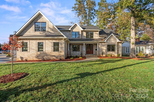craftsman-style home featuring a front yard, brick siding, and roof with shingles