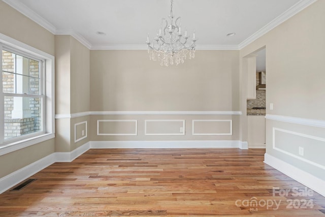 spare room with a chandelier, crown molding, light wood-style flooring, and baseboards