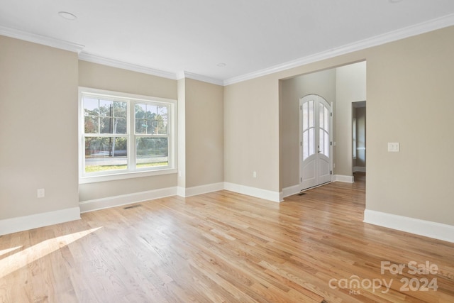 unfurnished room featuring crown molding, light wood-style floors, baseboards, and french doors