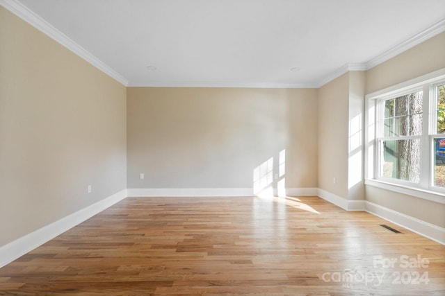 spare room featuring ornamental molding, baseboards, and light wood finished floors