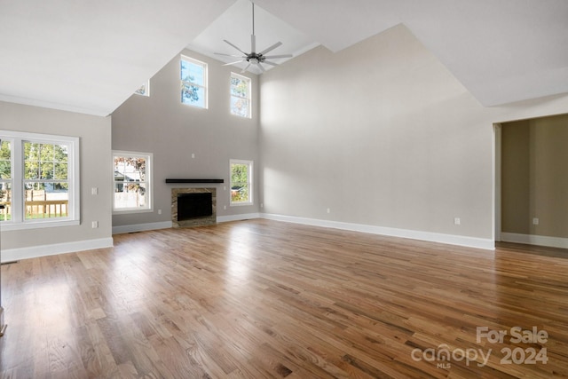unfurnished living room with plenty of natural light, wood finished floors, a ceiling fan, and a towering ceiling