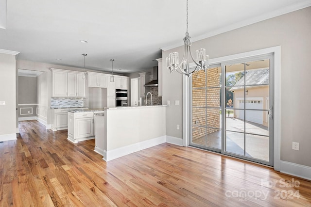kitchen featuring a chandelier, light wood-style flooring, white cabinets, decorative backsplash, and stainless steel double oven