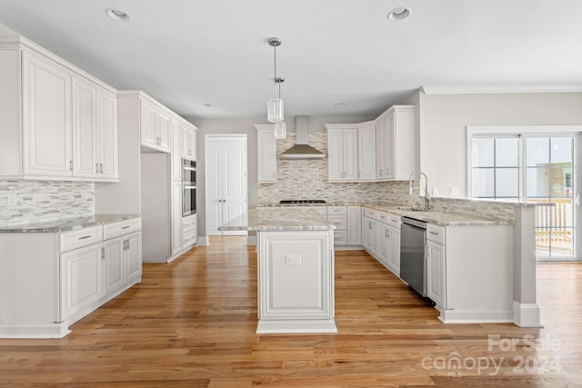 kitchen with white cabinetry, wall chimney range hood, a center island, and appliances with stainless steel finishes