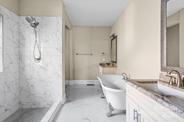 bathroom featuring marble tiled floors, tiled shower, a soaking tub, two vanities, and baseboards