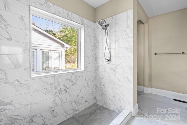 bathroom with tiled shower, marble finish floors, and baseboards
