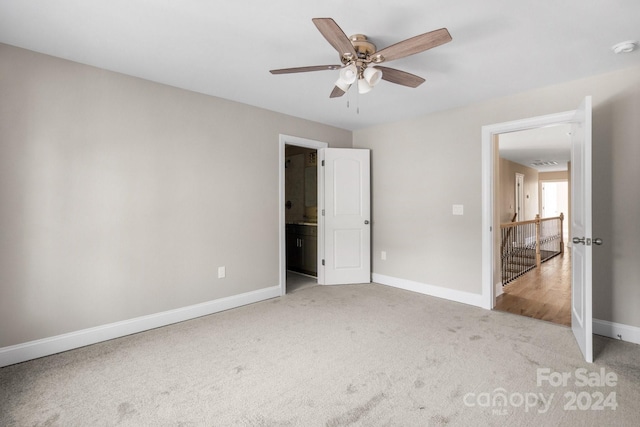 unfurnished bedroom featuring light carpet, baseboards, ensuite bathroom, and ceiling fan