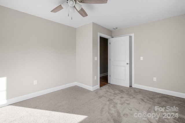 carpeted spare room with ceiling fan and baseboards