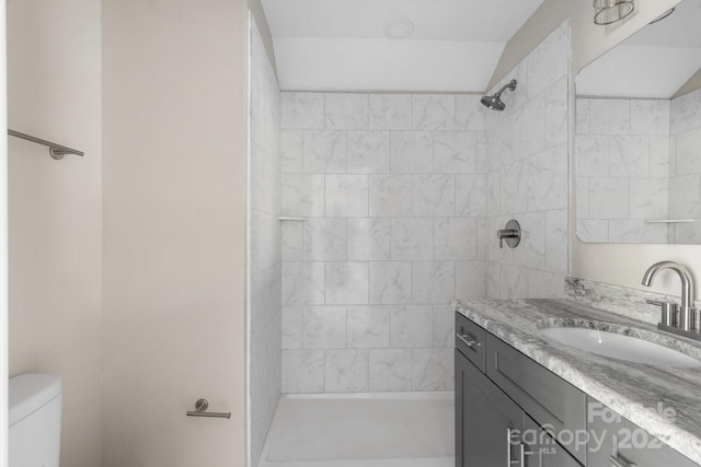 bathroom with tiled shower, vanity, and toilet