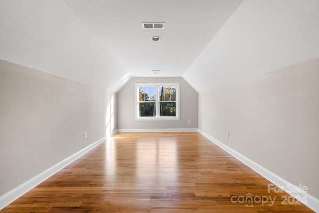 additional living space featuring lofted ceiling, light wood finished floors, and baseboards