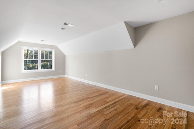 bonus room with light wood-style floors, lofted ceiling, and baseboards