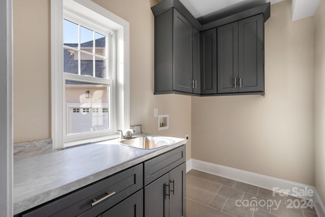 washroom with washer hookup, cabinet space, baseboards, and tile patterned flooring