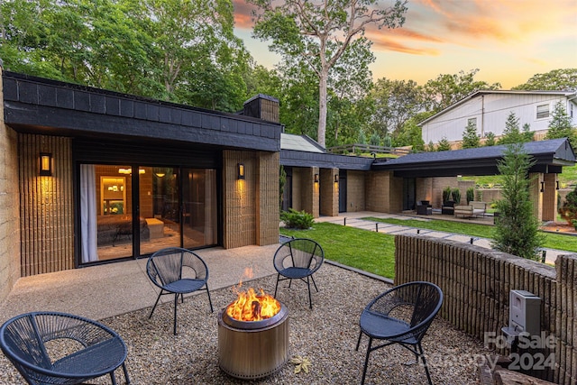 back house at dusk featuring a patio and an outdoor living space with a fire pit