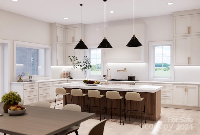 kitchen featuring a healthy amount of sunlight, a breakfast bar, light stone counters, and a kitchen island with sink