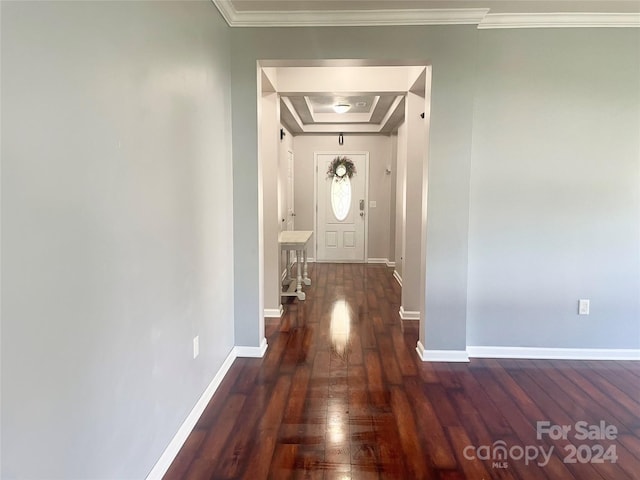 corridor featuring dark hardwood / wood-style flooring, a tray ceiling, and ornamental molding