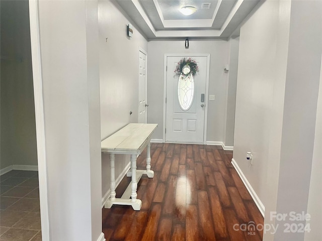 doorway to outside featuring a raised ceiling and dark wood-type flooring