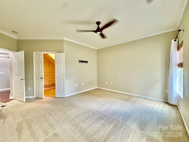 unfurnished bedroom with a spacious closet, ceiling fan, light colored carpet, and ornamental molding