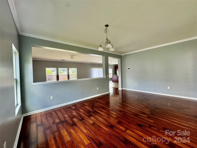 spare room featuring dark hardwood / wood-style floors, ornamental molding, and a chandelier