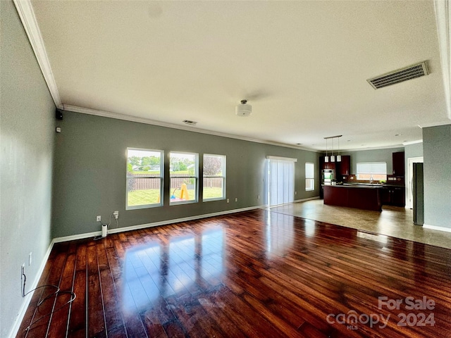 unfurnished living room featuring dark hardwood / wood-style floors, ornamental molding, and sink