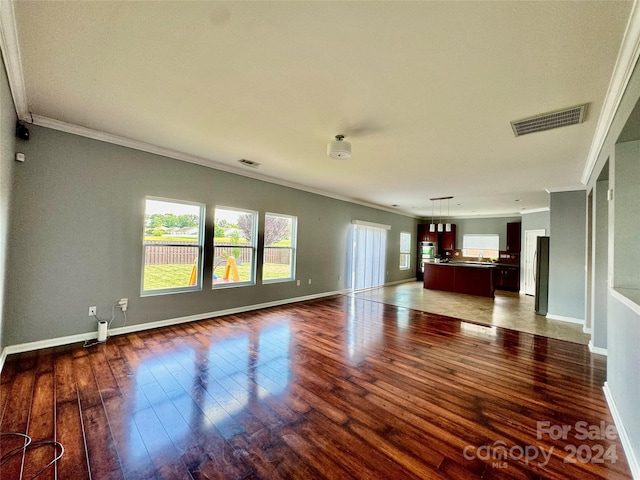 unfurnished living room featuring dark hardwood / wood-style flooring and ornamental molding