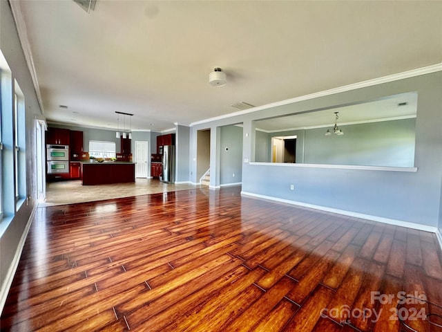 unfurnished living room featuring ornamental molding, dark wood-type flooring, and an inviting chandelier