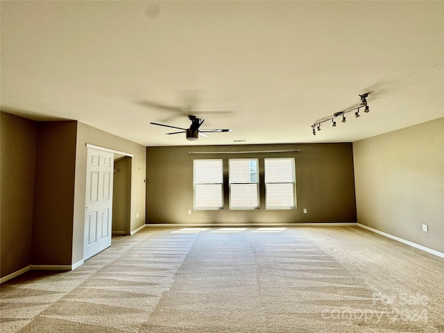 empty room with ceiling fan, light colored carpet, and track lighting