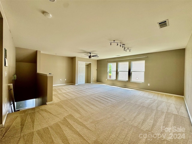 unfurnished living room with light colored carpet, track lighting, and ceiling fan