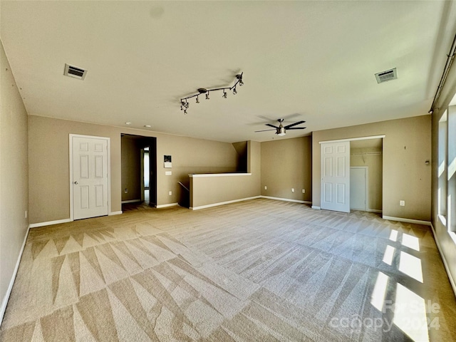 unfurnished living room featuring light carpet, rail lighting, and ceiling fan