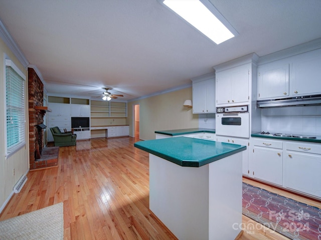 kitchen featuring white oven, ceiling fan, light wood-type flooring, ornamental molding, and white cabinetry