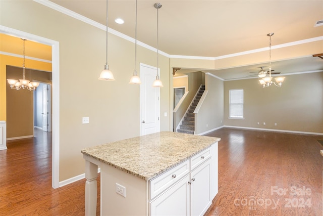 kitchen with pendant lighting, white cabinets, ceiling fan with notable chandelier, hardwood / wood-style flooring, and a kitchen island