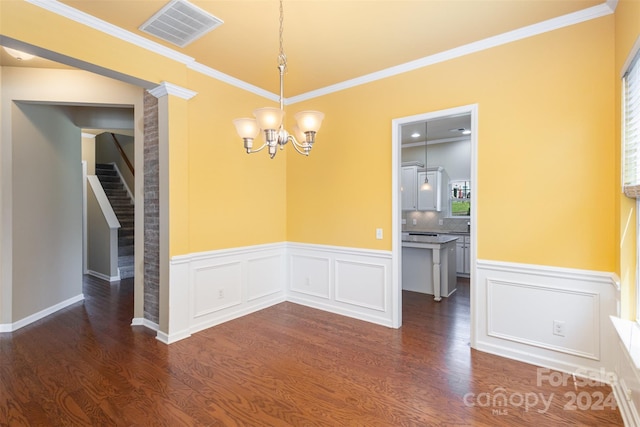 unfurnished dining area with dark hardwood / wood-style flooring, ornamental molding, and a chandelier