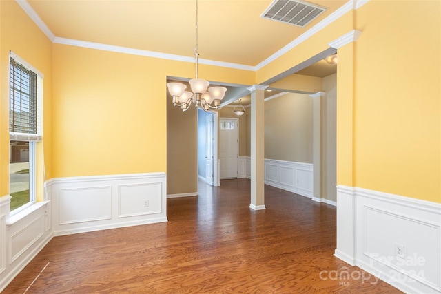 unfurnished dining area with crown molding, ornate columns, dark wood-type flooring, and a chandelier