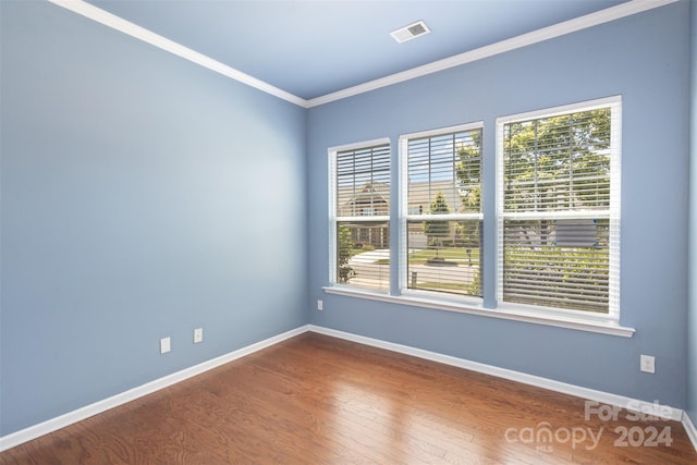 empty room with hardwood / wood-style flooring and crown molding