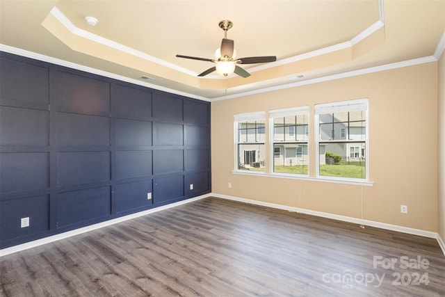 spare room with a tray ceiling, ceiling fan, hardwood / wood-style floors, and ornamental molding