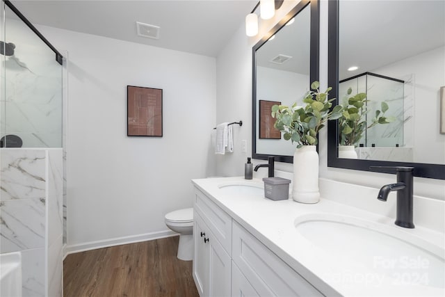 bathroom featuring toilet, hardwood / wood-style floors, a shower with shower door, and vanity