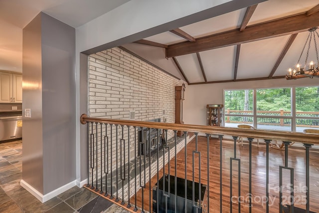 hall featuring a notable chandelier, lofted ceiling with beams, and brick wall