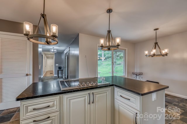 kitchen featuring cooktop, white cabinetry, a kitchen island, a notable chandelier, and pendant lighting