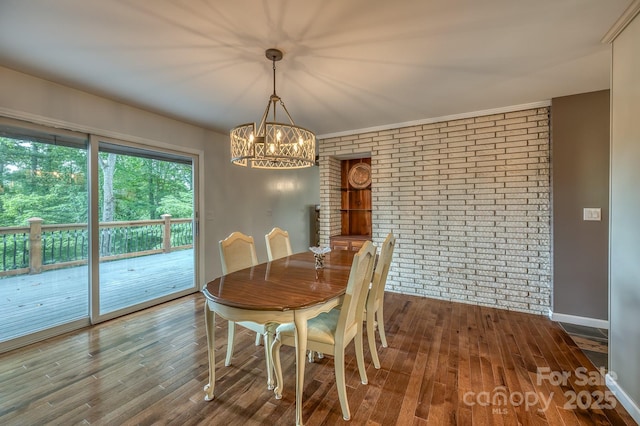 dining space featuring brick wall and dark wood-type flooring