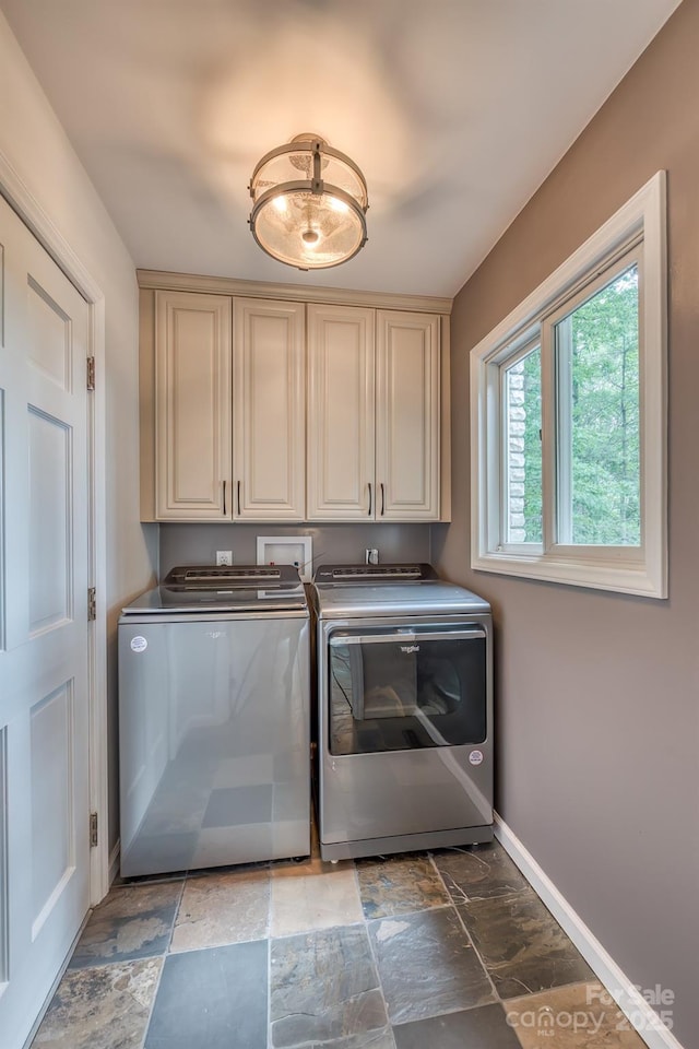 clothes washing area featuring cabinets and washing machine and clothes dryer